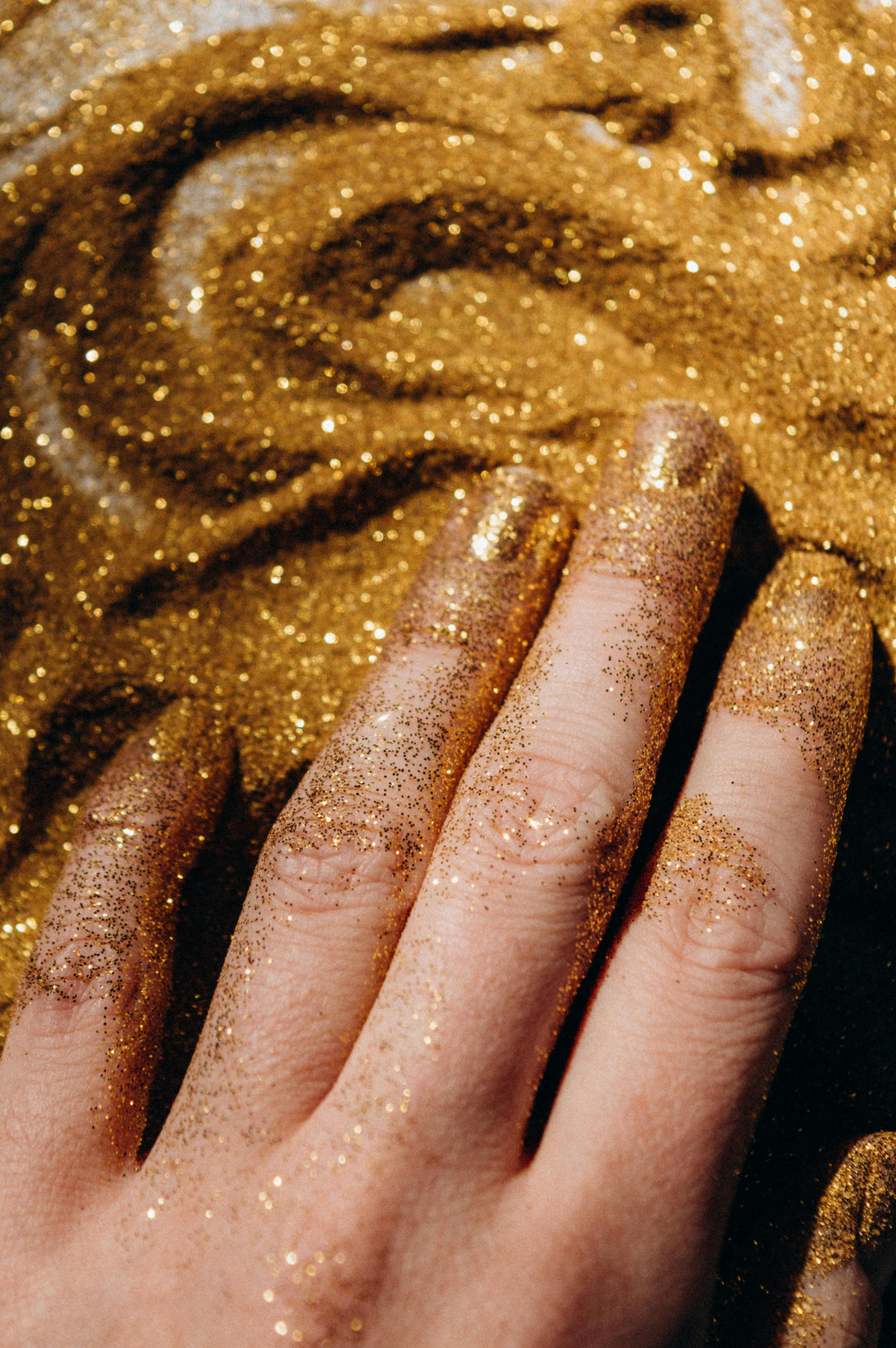 close up shot of a person touching gold glitters