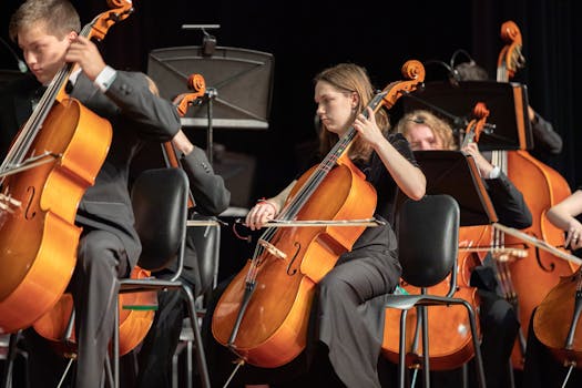 Orchestra cellists performing classical music in an indoor concert setting.