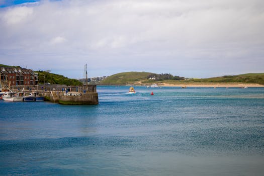 Serene harbor scene with boats and a 'Slow Speed' sign, under a partly cloudy sky.
