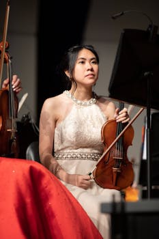 Asian woman in a white dress holding a violin, prepared for a musical performance.