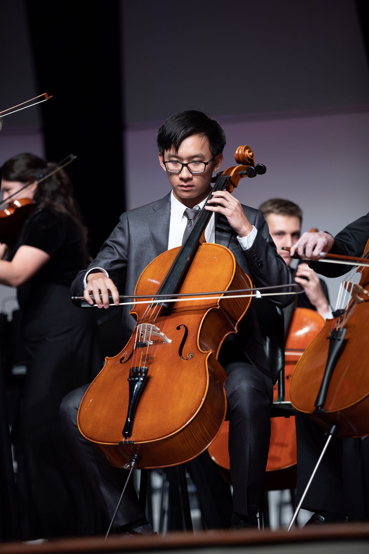 Cellist performing on stage during an orchestral concert