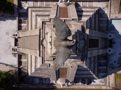 Free Drone shot capturing a grand monument with a prominent bird sculpture viewed from above. Stock Photo