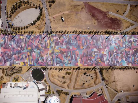 Colorful aerial view showcasing a decorated urban street with abstract patterns and surrounding landscape.