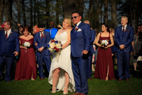 A Man in Blue Suit and a Woman in White Wedding Dress Smiling and Posing