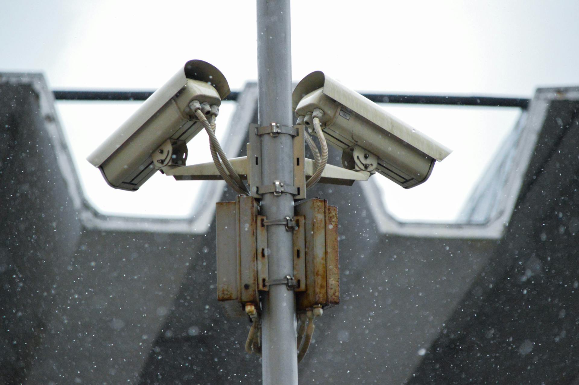 Close-up view of surveillance cameras during a snowfall in urban Москва setting.