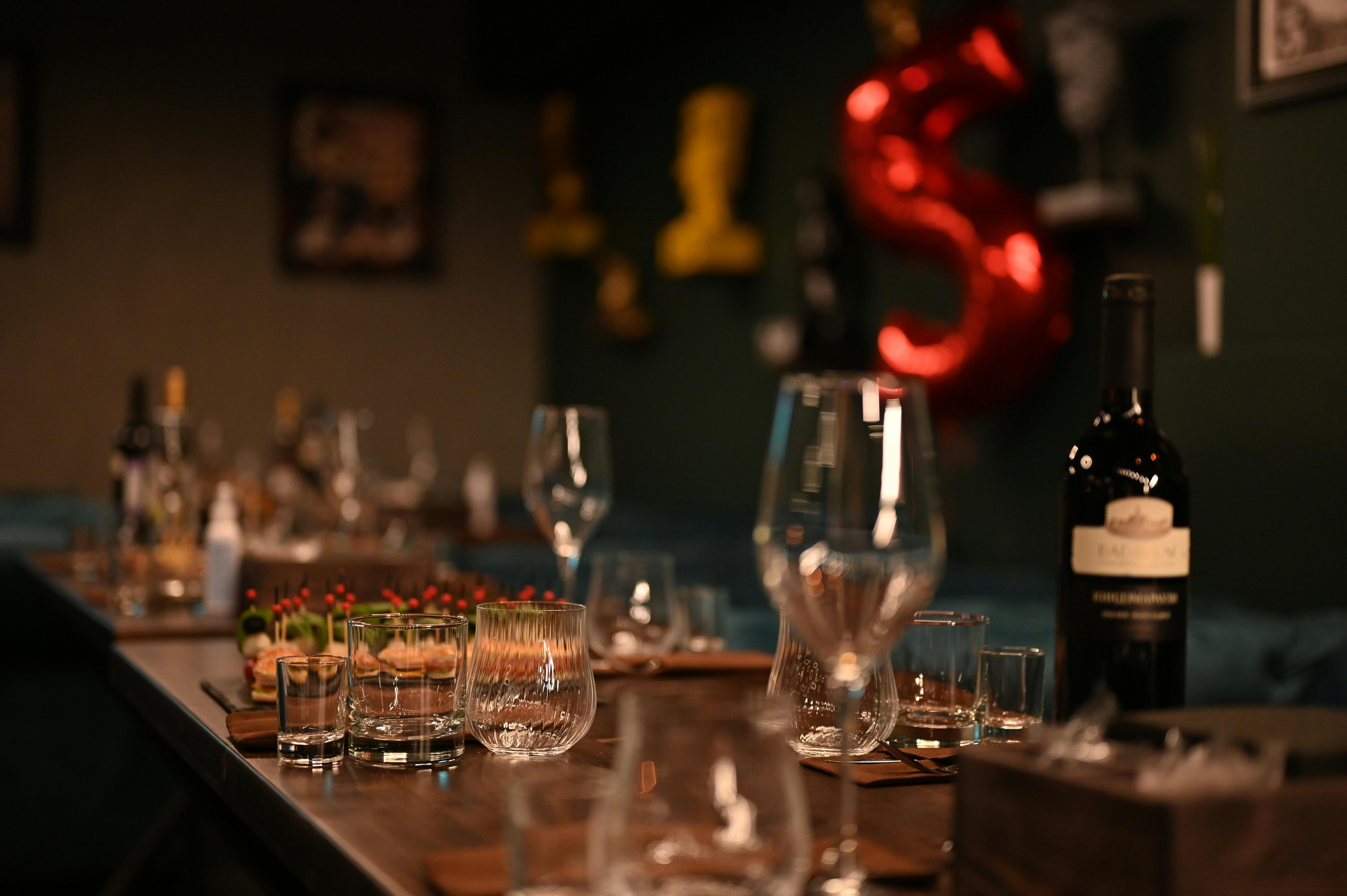 An indoor table setup featuring wine bottles and glassware, creating an elegant ambiance for a dinne