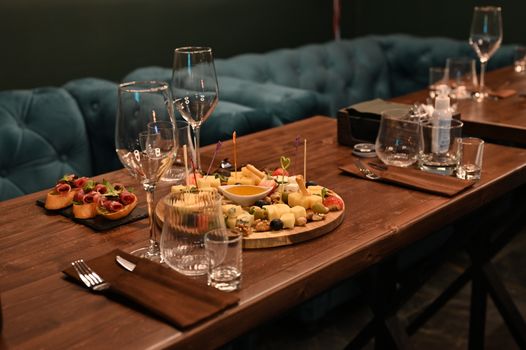 A beautifully arranged charcuterie and cheese platter on a rustic wooden table in a stylish restaurant setting.
