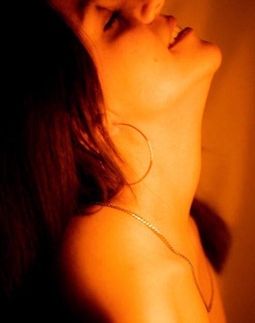 Free Artistic side view portrait of woman with hoop earrings and necklace, bathed in warm light. Stock Photo