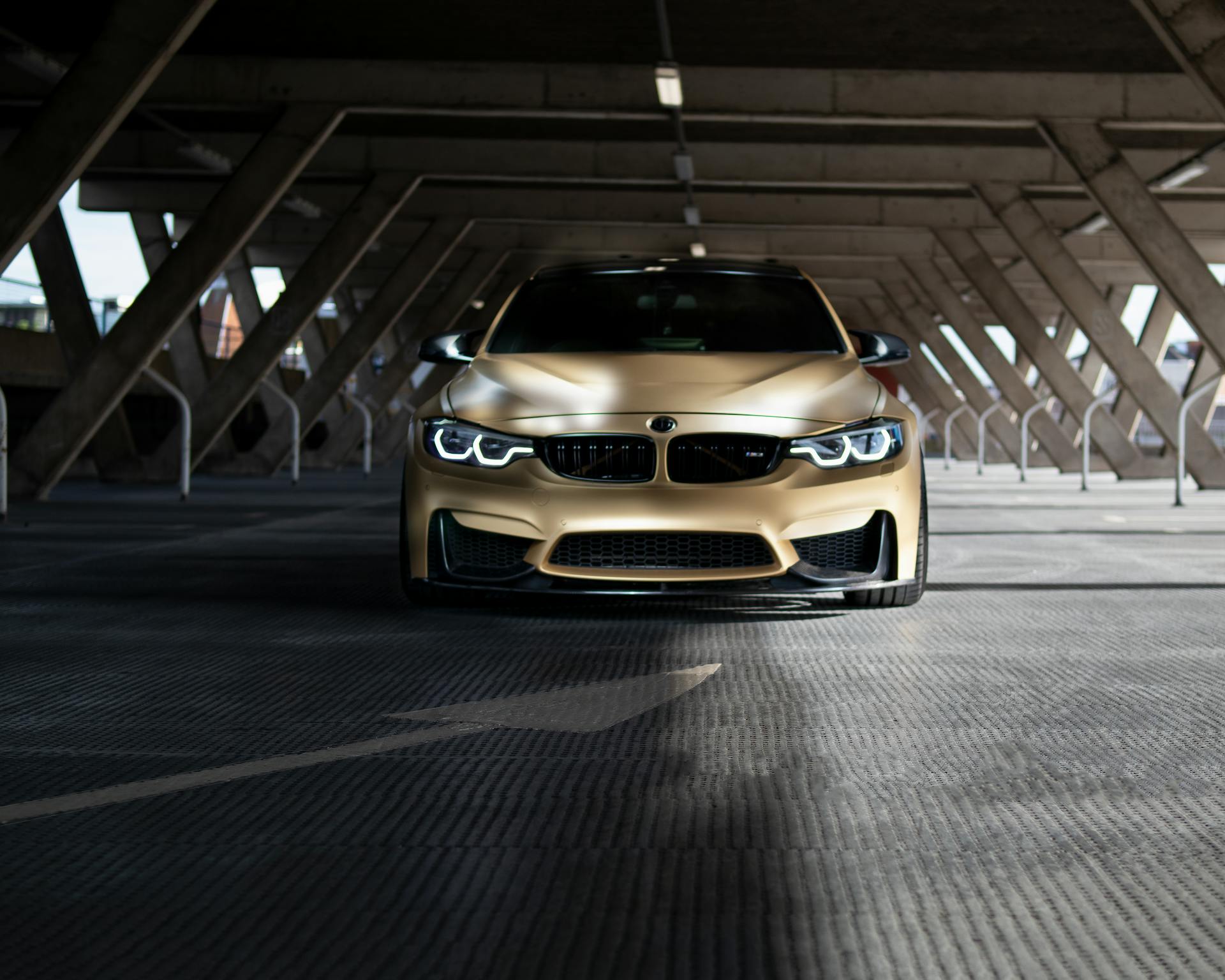 Front view of a luxury BMW coupe parked in an urban setting under a parking structure.