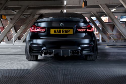 Free Rear view of a sleek, black luxury car parked in an urban garage setting. Stock Photo