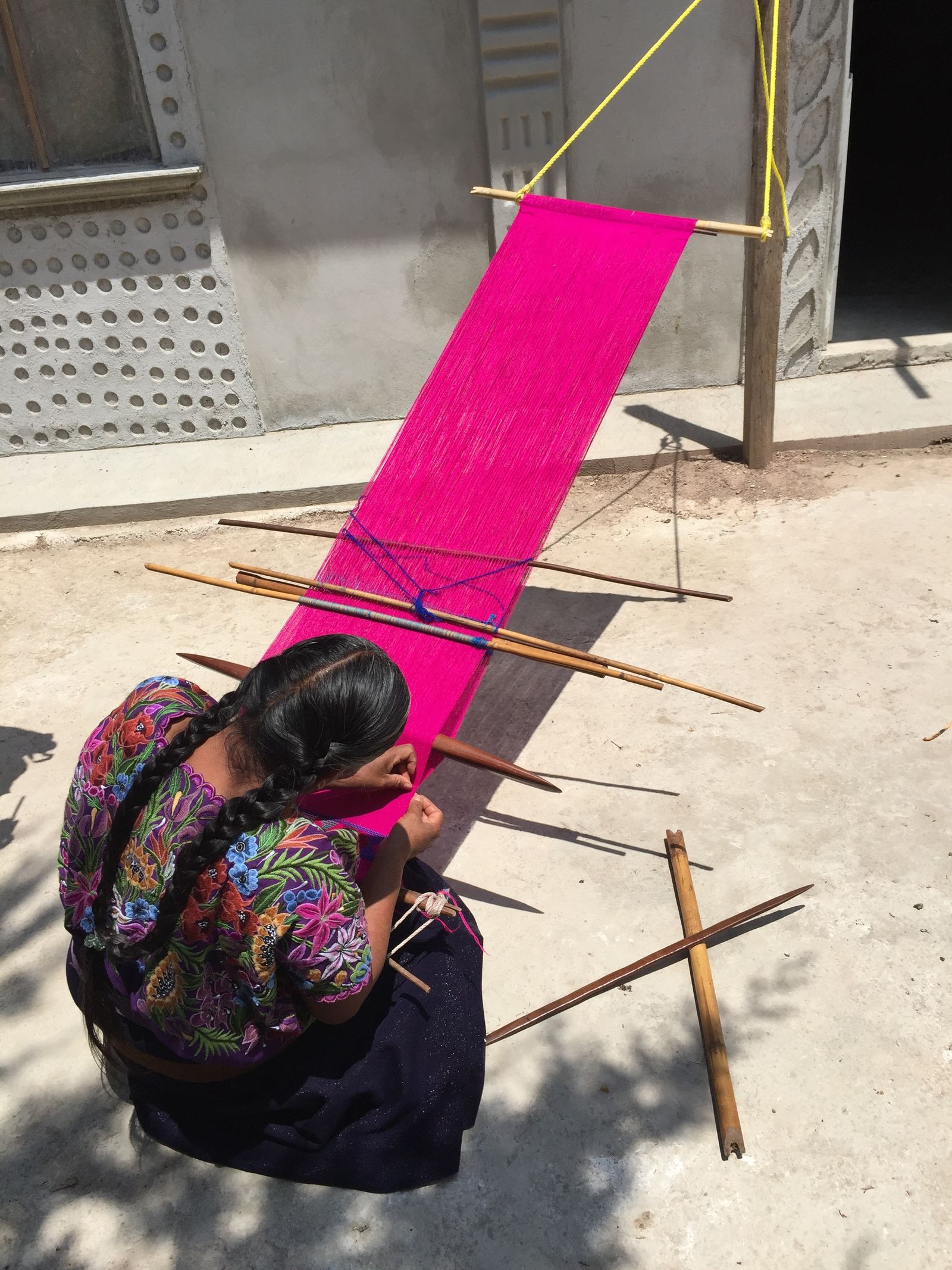 An artisan weaving a bright textile