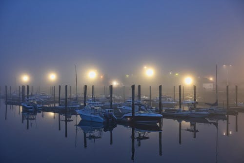 View of Boats Moored in a Marina Covered in Fog in the Evening