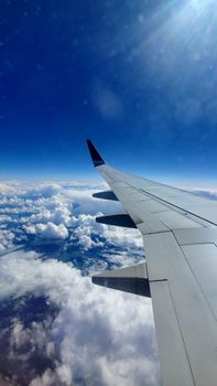 A stunning view of airplane wing and clouds against a vibrant blue sky, captured mid-flight.