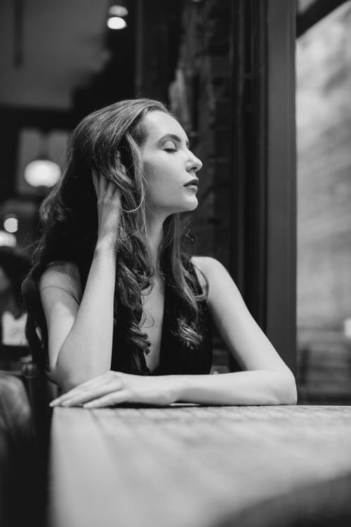 Free Black and white portrait of a woman sitting by a window in a restaurant. Stock Photo