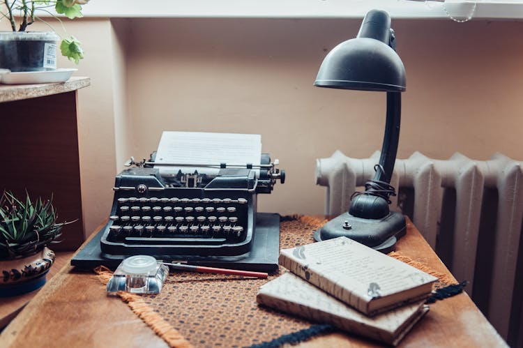 A Black Typewriter And Black Desk Lamp On The Table