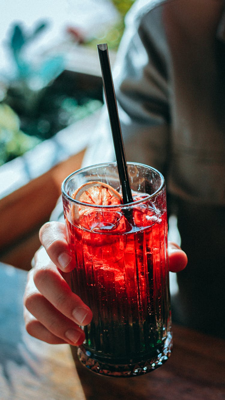 Person Holding A Red Juice With A Slice Of Lemon 