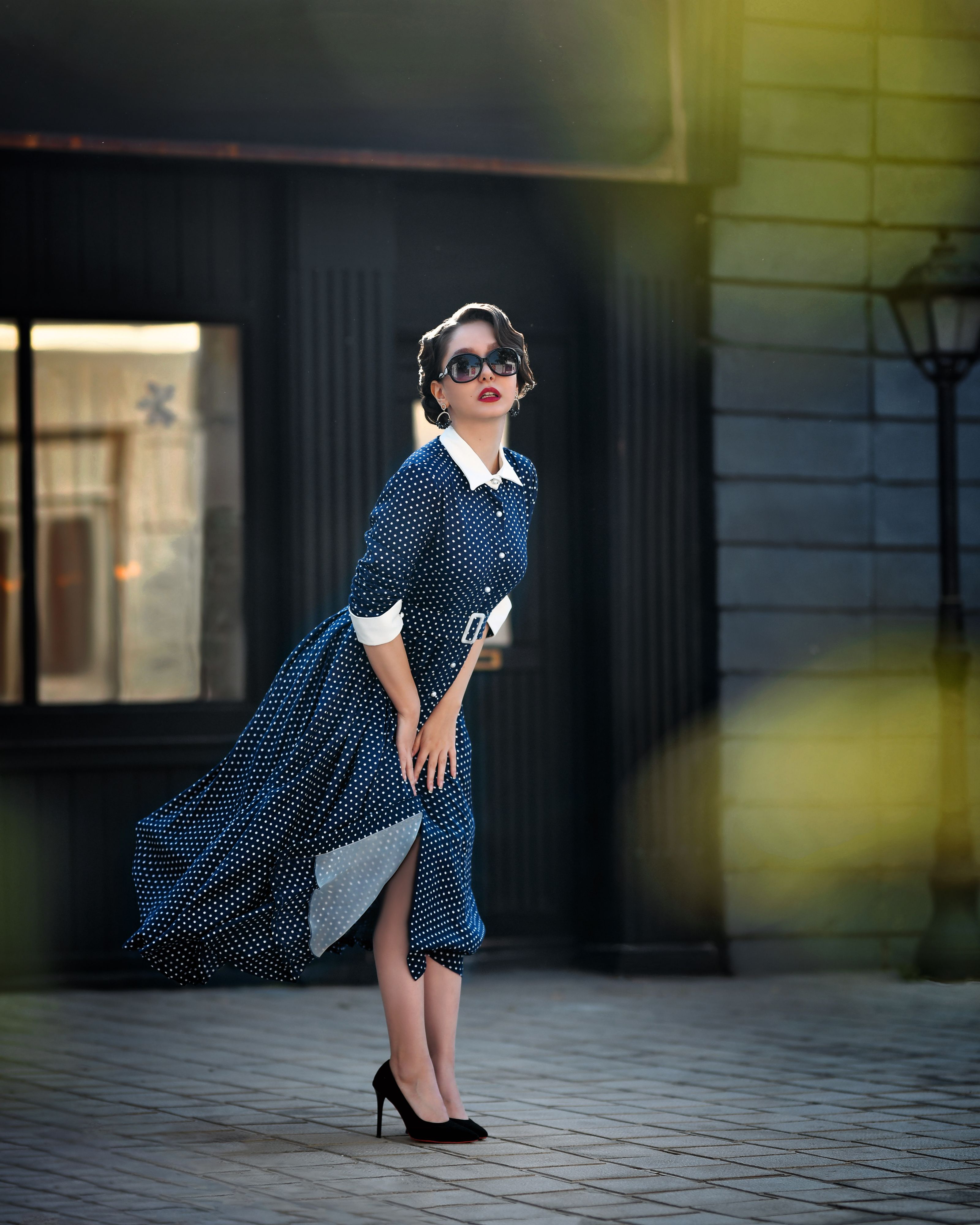 Mulher com estilo vintage em vestido de poá posando com elegância ao ar livre.