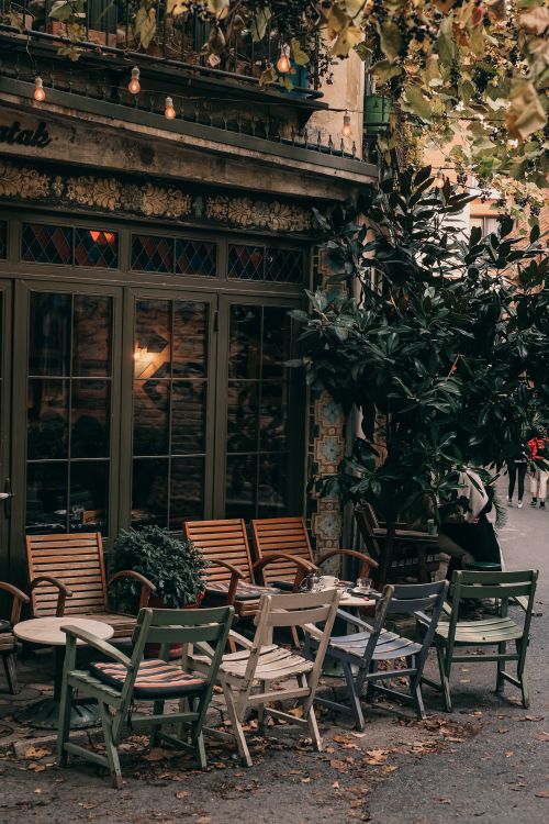 Free Charming outdoor bistro with wooden tables and chairs, surrounded by lush greenery. Stock Photo