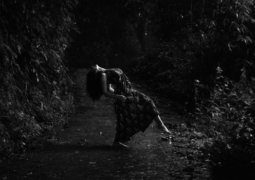 Elegant depiction of a woman dancing in a lush forest setting, captured in monochrome.