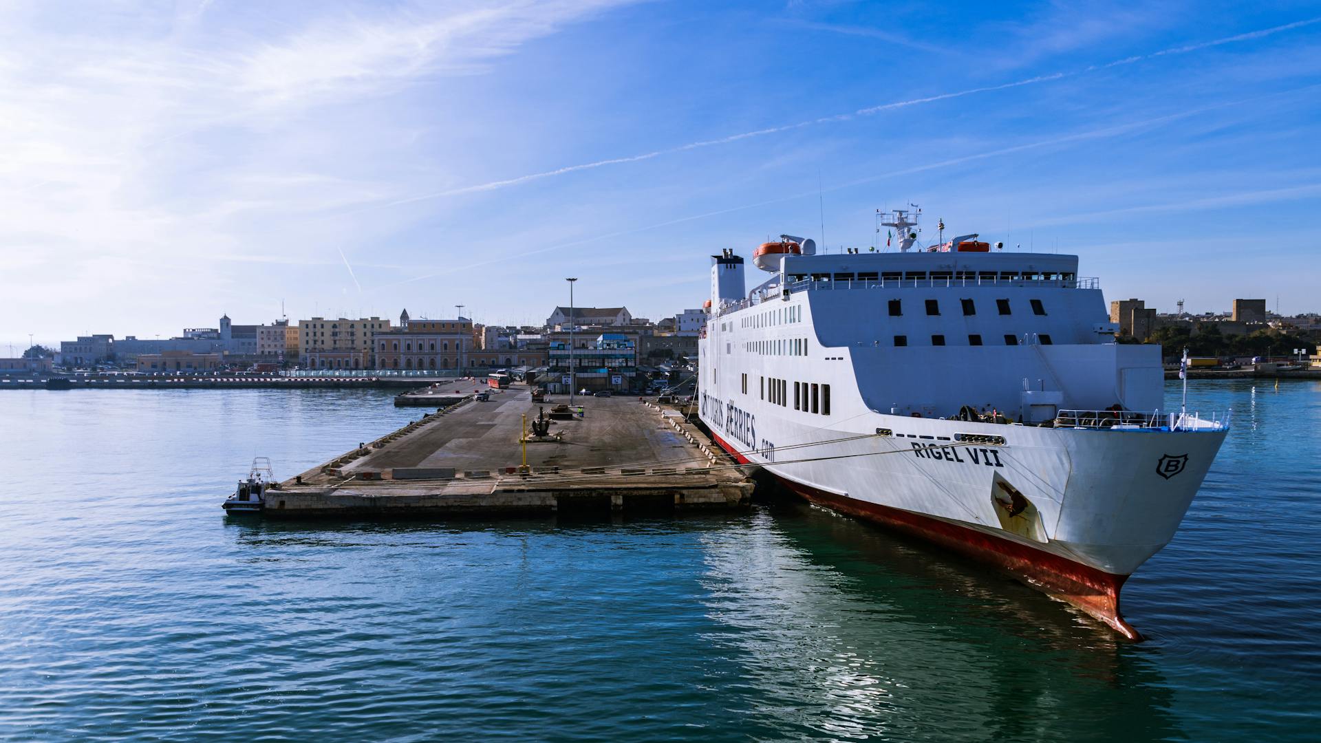 Large white ferry moored in Bari harbor, Apulia, under a clear blue sky.