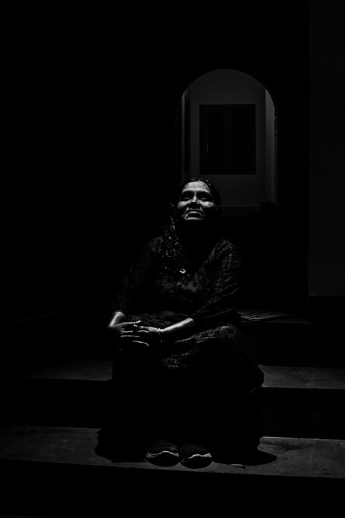 Free Introspective black and white portrait of a woman sitting on steps, captured in dramatic lighting. Stock Photo