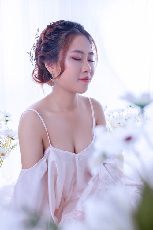 Free Elegant portrait of a woman with braided hair and closed eyes surrounded by white flowers. Stock Photo