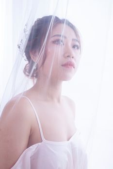 Elegant portrait of a woman through sheer fabric, conveying a dreamy and ethereal mood.