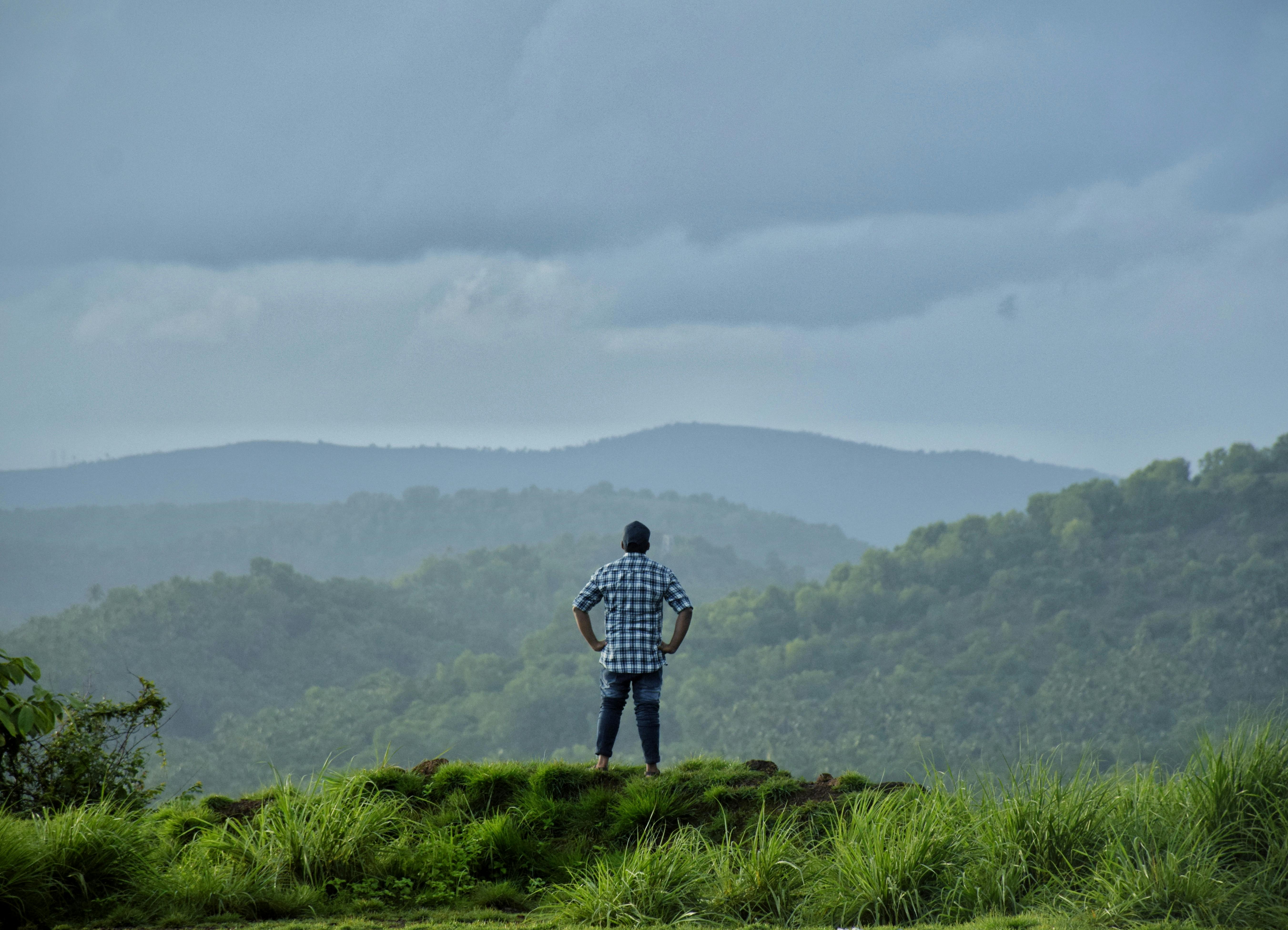Person Looking Afar Standing on Mountain Summit · Free Stock Photo