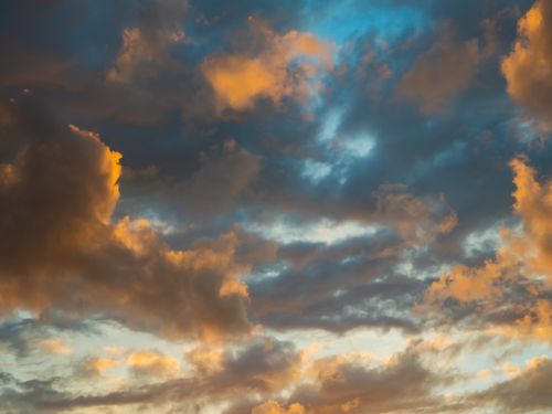 Free A stunning view of a sunset sky with vibrant clouds illuminated by the setting sun. Stock Photo