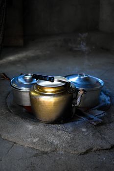 A vintage metal kettle and pots on a rustic stone stove evoke a retro kitchen ambiance.