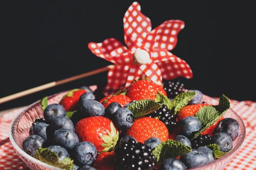 Free A vibrant mix of fresh berries in a bowl with a decorative pinwheel, perfect for summer and healthy eating. Stock Photo