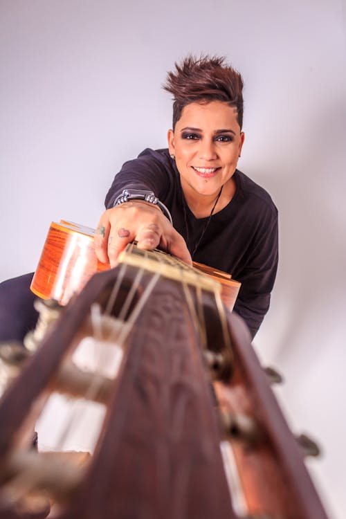 Woman Pointing Out Her Classical Guitar to Camera