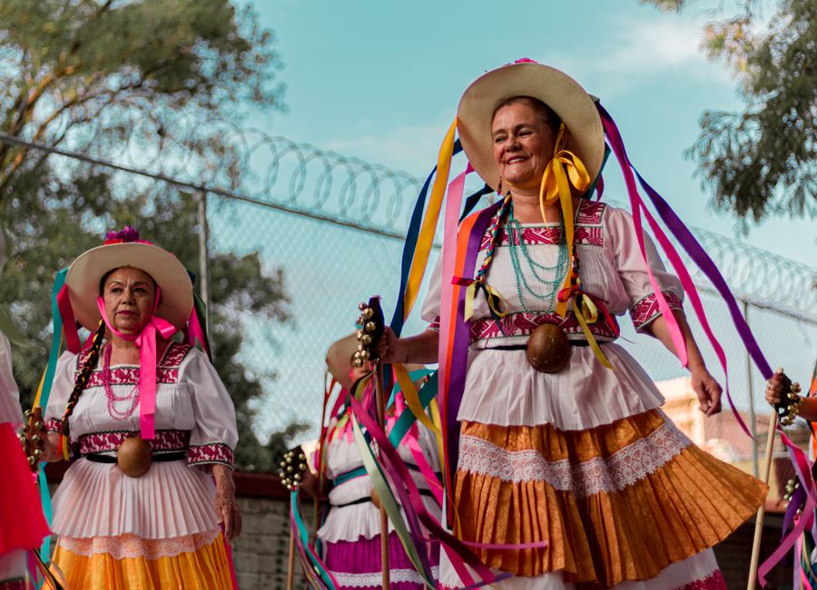 Vibrant display of Mexican heritage with women in colorful traditional costumes at a festival.