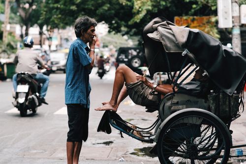 Free Candid street scene featuring a conversation between two men near a rickshaw in an urban setting. Stock Photo