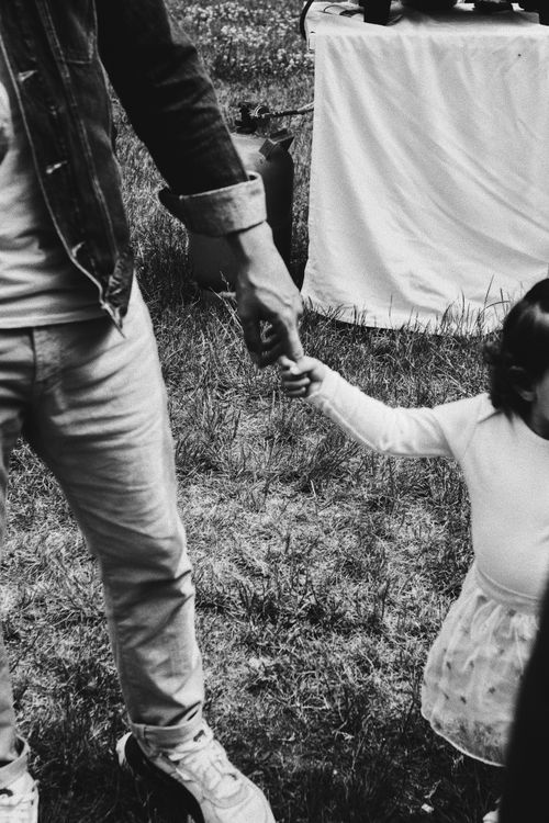 Free Black and white photo of father holding daughter's hand in Berlin park, showcasing parent-child bond. Stock Photo