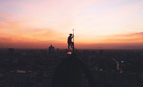 Statue on Roof in City during Sunset