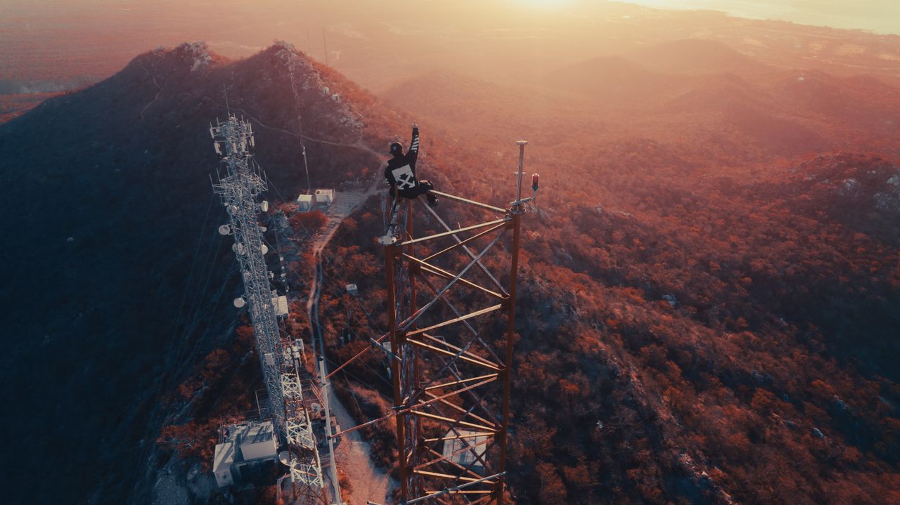 adventurous person atop a communications tower at sunset in mexico cit