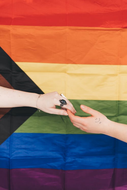 Free Hands Touching against Progress Pride Flag Stock Photo