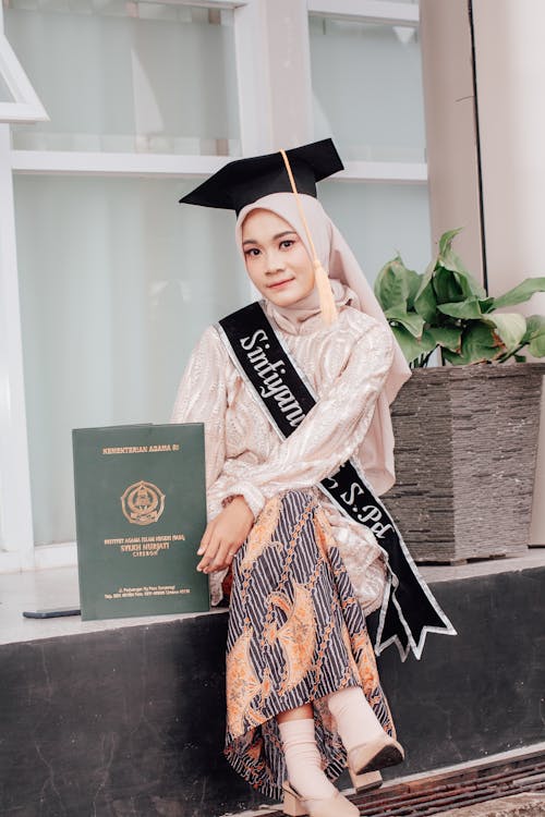 Young Woman Wearing a Hijab and a Mortarboard Holding Her Graduation Diploma