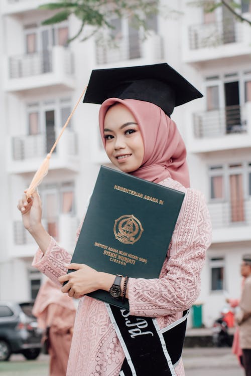 Young Woman Wearing a Hijab and a Mortarboard Holding Her Graduation Diploma 