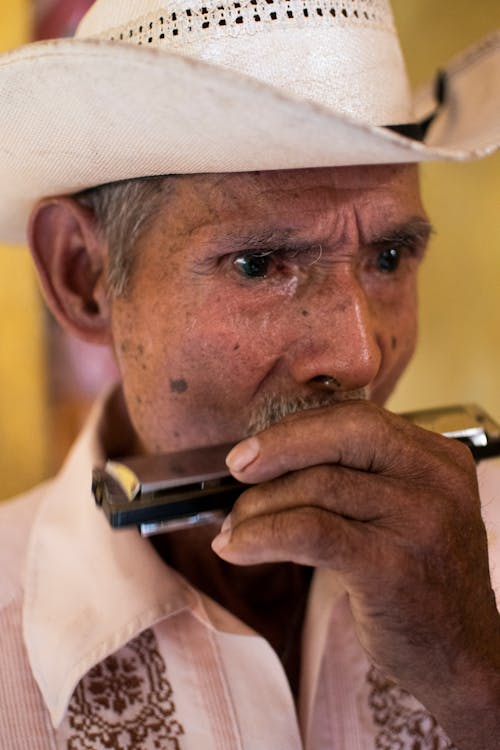 Elderly Man Wearing Cowboy Hat Playing Harmonica