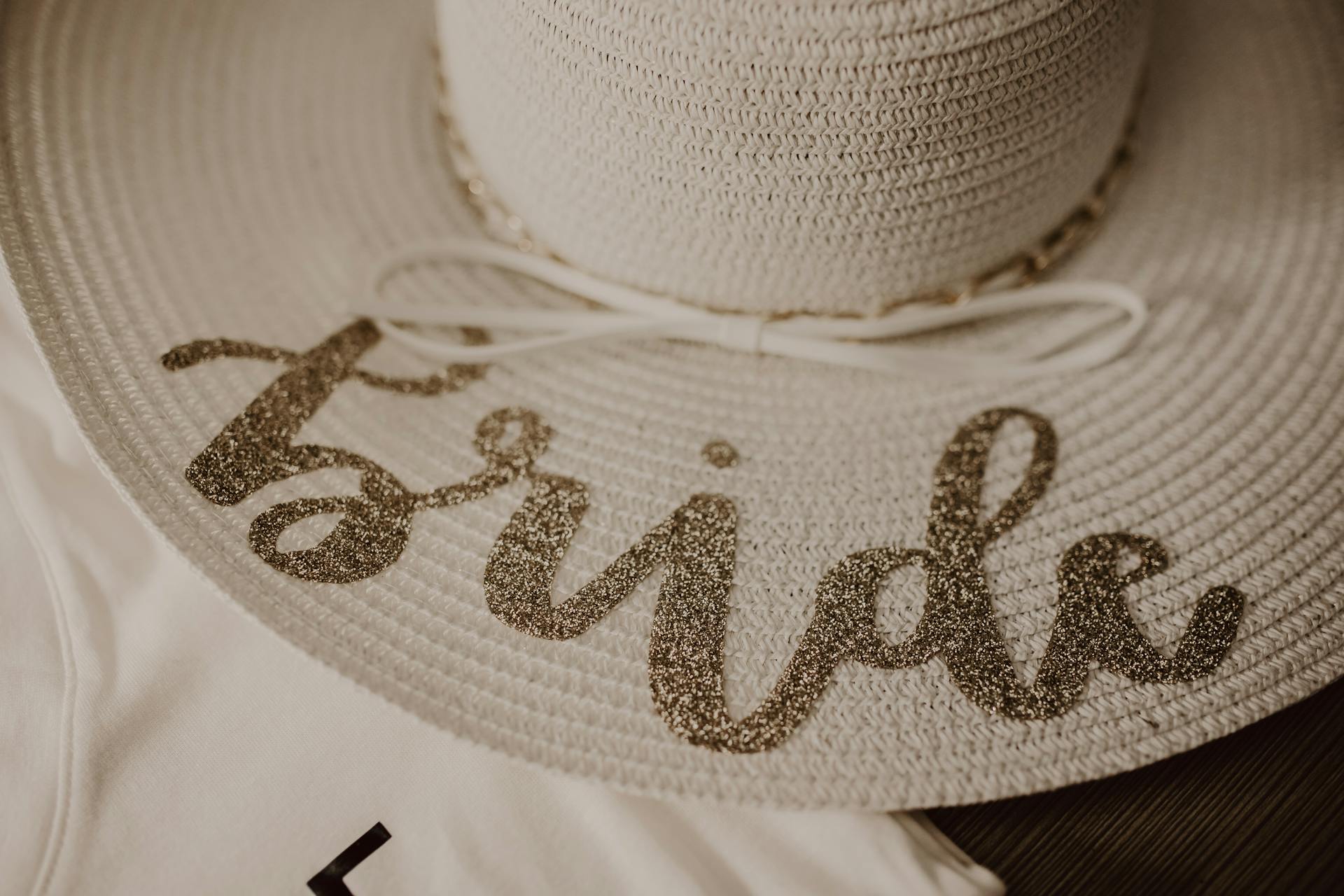 Close-up of a stylish straw hat with glittery 'bride' text, perfect for a wedding or bachelorette party.