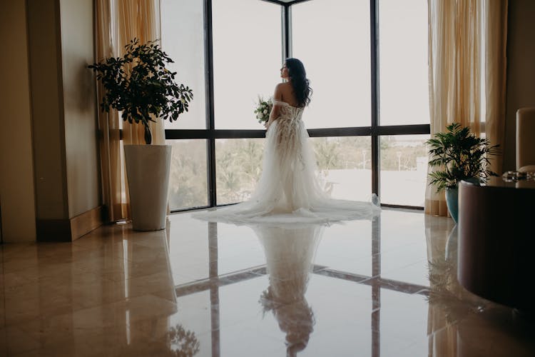 Bride In Wedding Dress Standing By Window