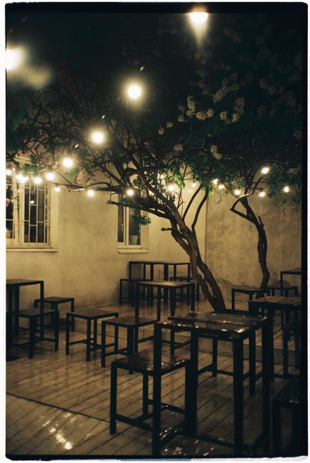 Atmospheric outdoor patio scene with hanging lights and empty tables during nighttime.