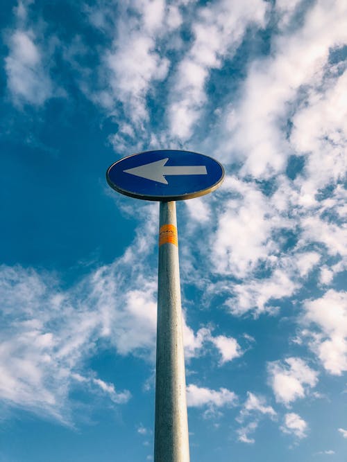 White and Blue Arrow Sign Under Blue and White Cloudy Sky