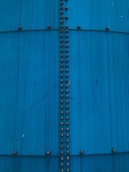 Detailed view of a blue painted metal surface featuring rows of screws and vertical lines.