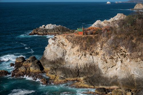 Free Breathtaking view of a rocky coastline, capturing waves crashing against cliffs under a clear blue sky. Stock Photo