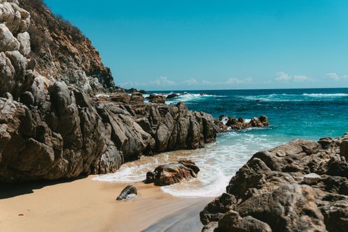 Free A beautiful rocky beach with turquoise ocean waves and clear blue skies. Stock Photo