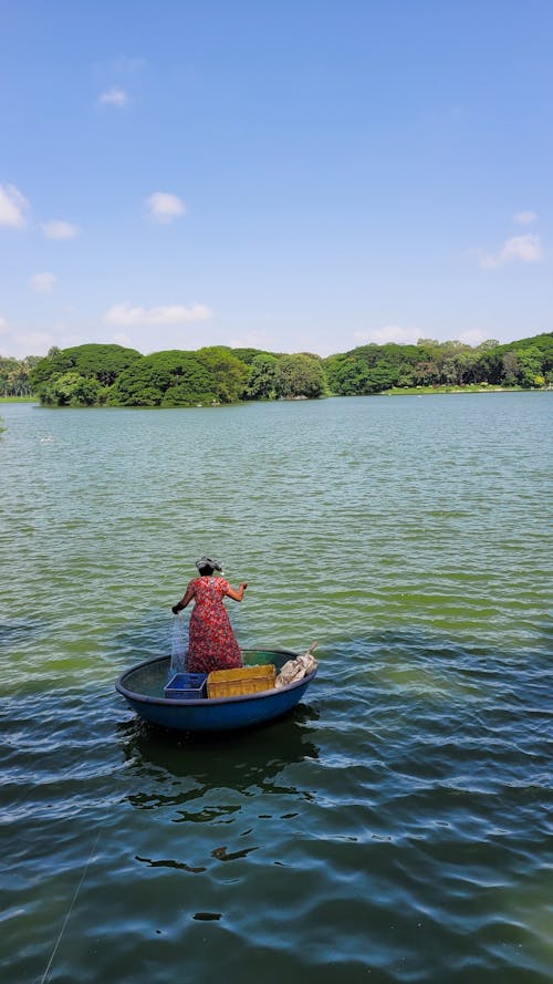 Woman in Red Dress Riding on Round Boat and Fishing