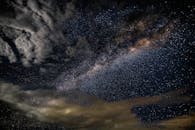 这张令人惊叹的照片捕捉到了布满星星和云的银河系，映衬在黑暗的夜空中